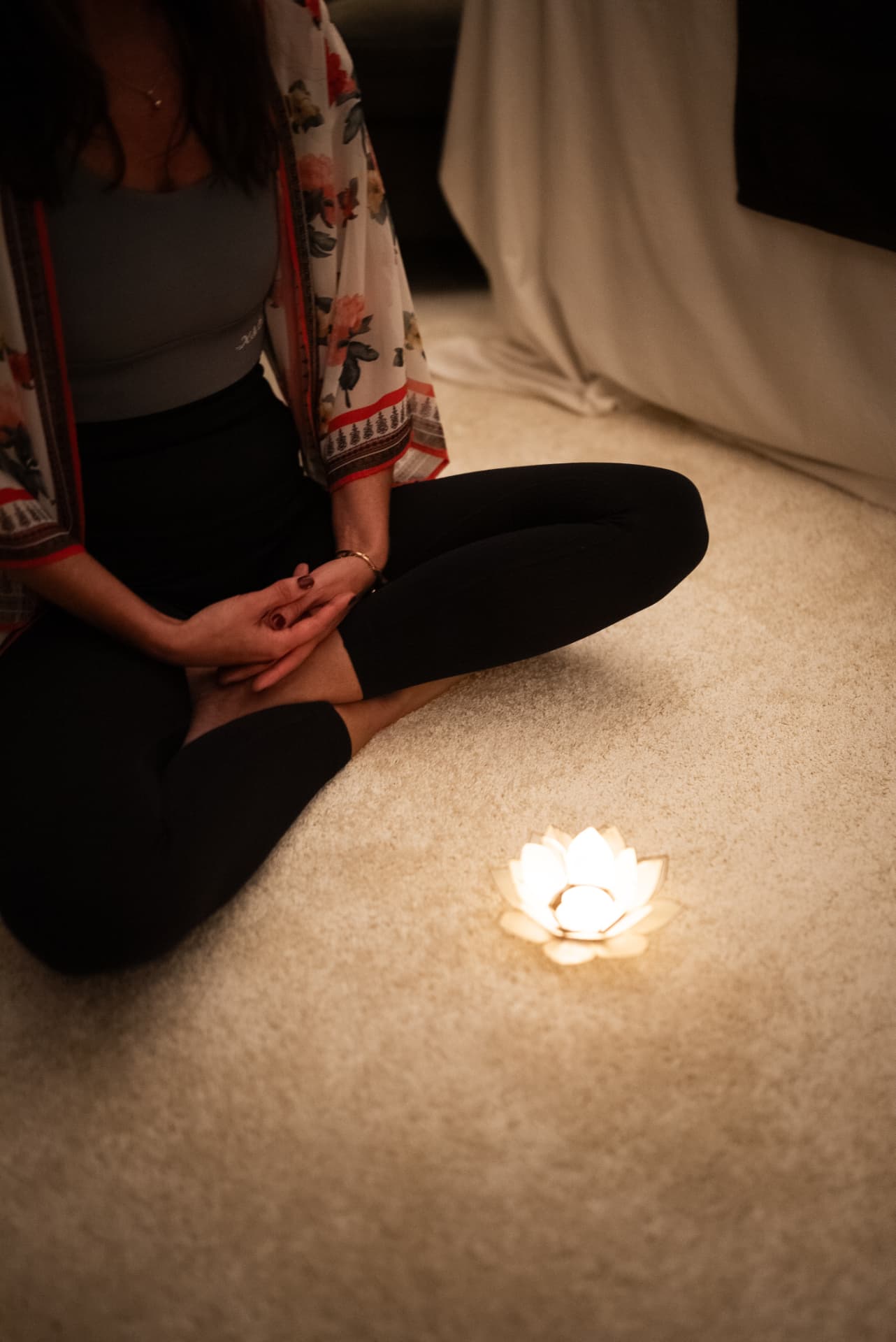 Sara sitter i stilla meditation i lotusposition med ett tänt lotusljus