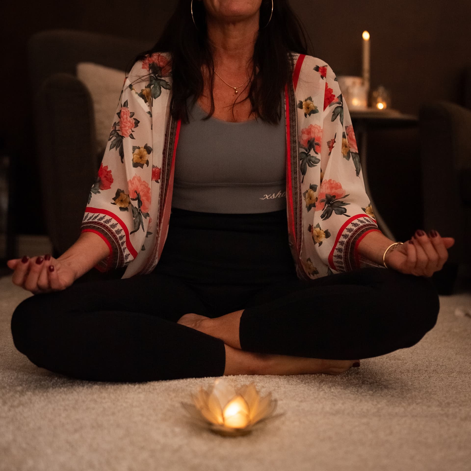 Sara sitter i stilla meditation framför ett tänt ljus